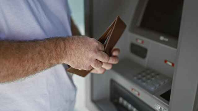 Handsome middle-aged caucasian man outside on urban street, captivating portrait of him holding wallet counting australian cash dollars at atm machine, engaging in banking transaction.