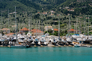 Fototapeta na wymiar Yachts and sailboats docked at a marina, nestled in a lush, mountainous coastline, under the Mediterranean sun