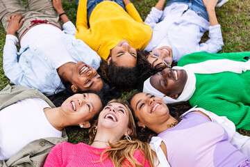 Diverse happy woman bonding together at city park. Multiracial group of female friends lying in...