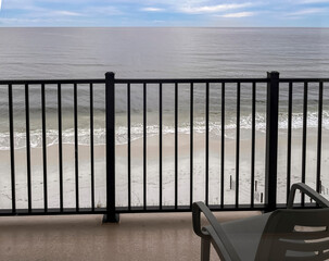 A balcony with a plastic chair overlooking a beach on the Gulf of Mexico in Florida.