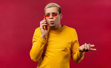 Stylish surprised man talking by phone, Having smartphone call on red background