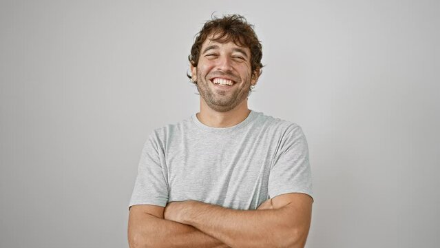 Confident young man with crossed arms, smiling happily at the camera over isolated white background