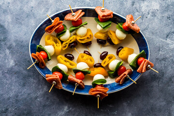 A dish of homemade antipasto skewers against a dark background.