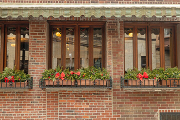 A beautifully decorated storefont with windows under a banner with rustic, beautiful brick in the North End of Boston. This restaurant outdoor space has holiday flowers and even afternoon lighting.