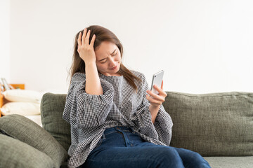 部屋でスマホを見る若い女性　考える