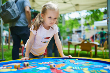 preschooler girl playing board game outdoors