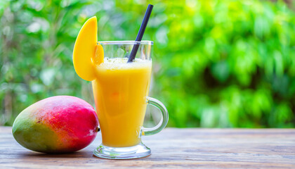 Fototapeta premium Fresh tropical fruit smoothie mango juice and fresh mango on a outdoor tropical background. Copy space.
