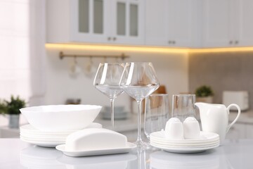 Set of clean dishware and glasses on table in kitchen