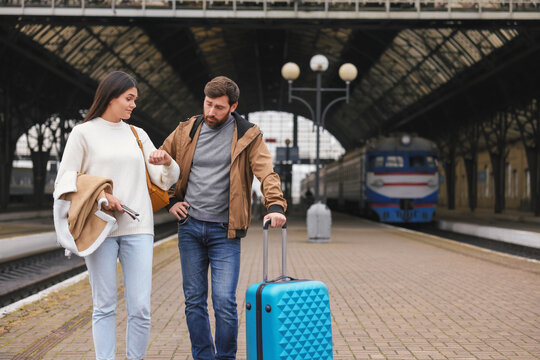 Being late. Worried couple with suitcase waiting at train station, space for text