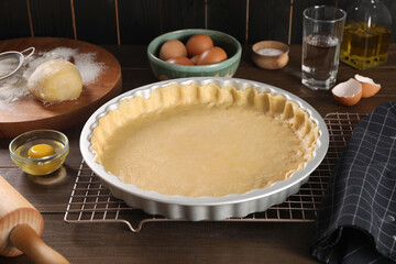 Pie tin with fresh dough and ingredients on wooden table. Making quiche