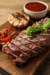 Delicious grilled beef steak with spices and tomato sauce on table, closeup