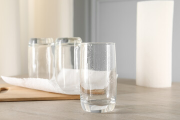 Clean glasses and paper towels on light wooden table