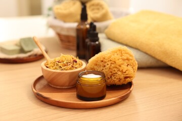 Dry flowers, loofah and jar with cream on wooden table indoors. Spa time