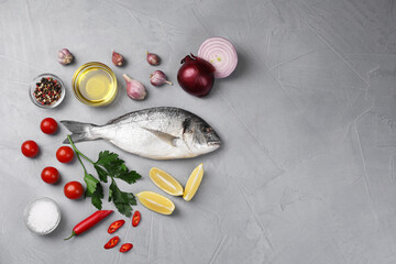 Flat lay composition with raw dorado fish and vegetables on grey table. Space for text
