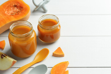 Tasty baby food in jars and ingredients on white wooden table, closeup. Space for text