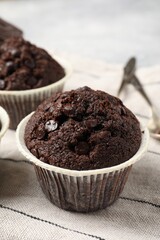 Tasty chocolate muffins and cloth on table, closeup