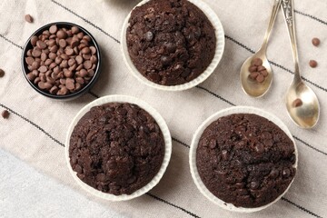 Tasty chocolate muffins and cloth on table, flat lay