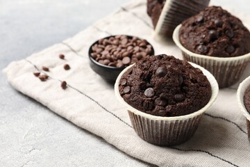 Tasty chocolate muffins and cloth on table, closeup. Space for text
