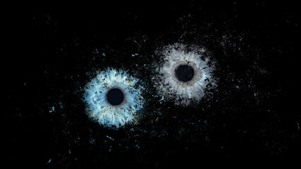 Galaxy explosion effect of human eyes colliding on black background. Close-up of blue and grey...