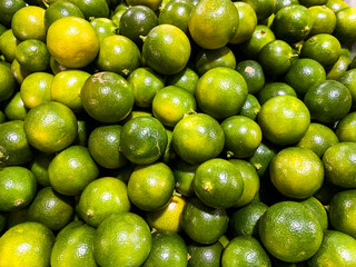 Top view of fresh green lemons as a background.
