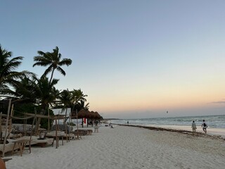 atardecer en una playa con camastros en la arena y palmeras