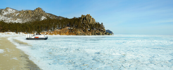 Lake Baikal in winter. A beautiful view of a frozen lake, a bay surrounded by mountains and forest,...