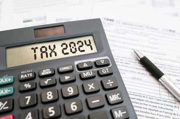 Word TAX 2024 on the calculator and personal income tax form. Business and tax concept.