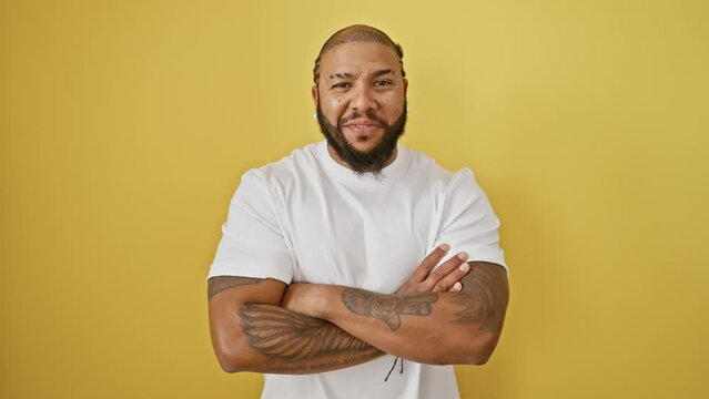 Handsome african american man with a big smile and crossed arms stands out on a yellow background, a grown-up portrait of natural happiness, confidence and friendliness.