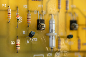 Electronic circuit board made of yellow fiberglass with soldered resistors and capacitors on metal...