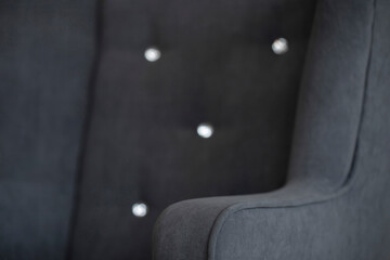 The side of an easy chair upholstered in plush gray fabric. Curved upholstered furniture...