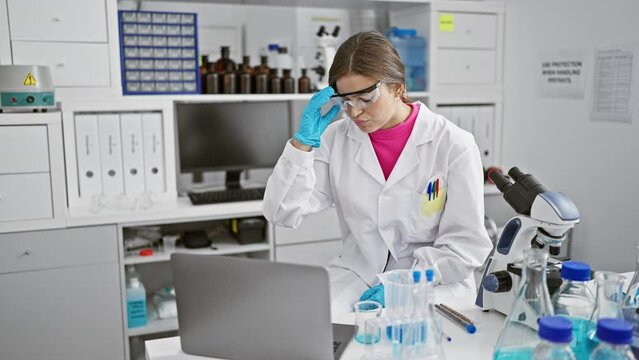 Stressed young beautiful hispanic woman scientist takes off glasses while struggling with tech issues at computer in lab
