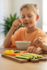 The boy reaches for fresh vegetables during lunch. Healthy eating.