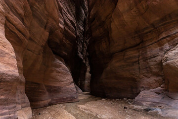 A shallow  stream flows between high rocks with beautiful amazing patterns on their walls at the end of a hiking trail in the Wadi Numeira gorge in Jordan
