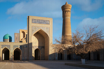 Obraz premium The main entrance and courtyard of the Kalyan Mosque - the main Friday mosque of Bukhara and the Kalyan Minaret in the background on a sunny day, Bukhara, Uzbekistan
