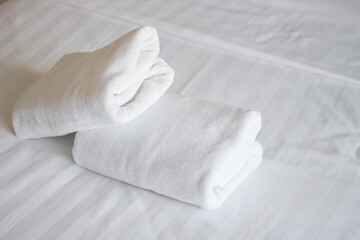 Stack of white towels on bed in hotel