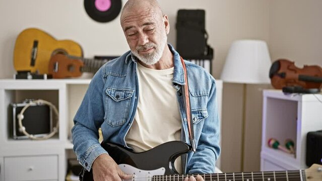 Mature man playing electric guitar in a modern home interior, showcasing musical passion and leisure activity at home