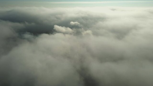 Flight above the clouds towards the sun. Misty weather, view from above. Birds point of view. Aerial camera shot.