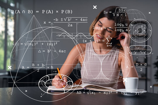 Smiling woman in casual wear taking notes in notebook at office workplace with coffee cup. Concept of distant business education, information technology, dreaming, thinking. Math drawings