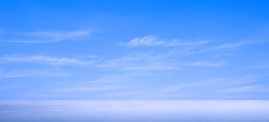 Blue sky panoramic background with beautiful softly cloud streaks over sea with daylight reflection...