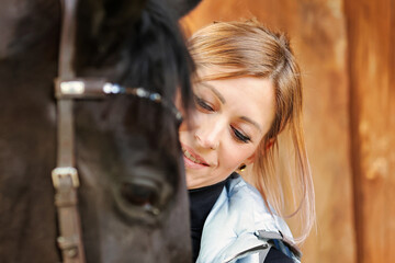 Girl blonde in blue quilted vest with ponytail plays with her horse, portraits of the woman with...