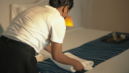Asia young maid chambermaid making bed in hotel room.