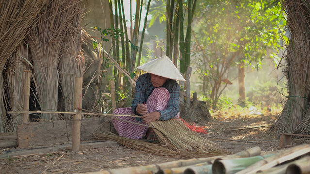 Title Asia life old femen grandmother working in outdoor. Old lady elderly serious living in the countryside of life rural people in thailand . Weaving material grass roof groof bamboo making.