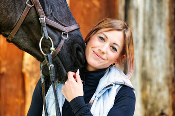 Girl blonde in blue quilted vest with ponytail plays with her horse, portraits of the woman with...