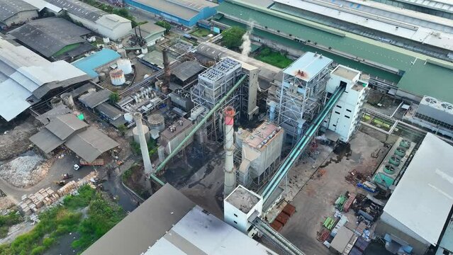 In front of the paper and packaging factory, a bustling scene unfolds, with numerous machines humming with activity, creating a symphony of industrial productivity. Aerial view drone. 4K footage
