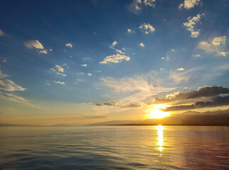 Colorful sunset on the sea. Mountain lake in the rays of the orange sun. Kyrgyzstan, Lake...