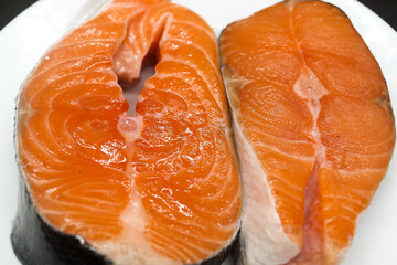 Two juicy salmon steaks on a white plate