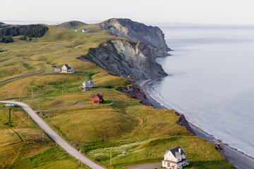 Fototapeta premium vue sur une falaise en bord de mer avec du gazon vert ainsi que des maisons et une route en été