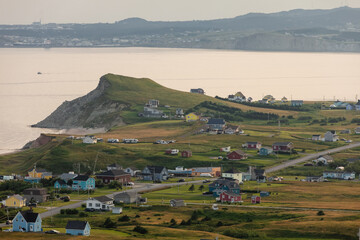 vue sur un village bord de mer avec du gazon vert ainsi que des maisons et une route en été