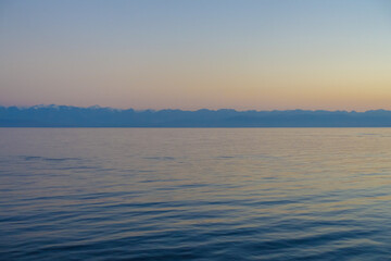 Colorful sunset on the sea. Mountain lake in the rays of the orange sun. Kyrgyzstan, Lake Issyk-Kul. natural background