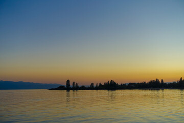 Colorful sunset on the sea. Mountain lake in the rays of the orange sun. Kyrgyzstan, Lake Issyk-Kul. natural background